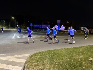 Zdjęcie przedstawia biegnących uczestników biegu - w tym funkcjonariusza KMP w Dąbrowie Górniczej podczas zabezpieczenia I Maratonu Zagłębiowskiego w dniu 23 maja 2026 roku.