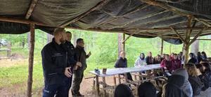 Umundurowani funkcjonariusze policji, straży pożarnej i straży leśnej na obozie harcerskim  dla młodzieży.