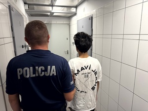 Umundurowany policjant i zatrzymany w pomieszczeniu dla osób zatrzymanych